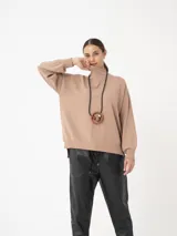 Sweater azul de cuello alto, con mangas amplias y puños ajustados.