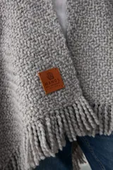 Ruana de tejido artesanal en lana merino, lino y viscosa, con textura aireada y terminación de flecos en los bordes. Diseño versátil y envolvente, ideal para usar como abrigo ligero.