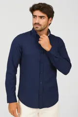 Camisa de algodón color azul marino, con cuello polo abotonado, cierre frontal de botones, manga larga con puños y un bolsillo frontal.
