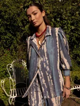 Blazer de edición limitada con estampado tie-dye en tonos azules y blancos, hombros sutilmente marcados y manga larga con puño ancho.