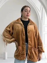 Campera de terciopelo color camel, con cierre frontal, cuello alto y bolsillos laterales con ribete de cuero sintético.