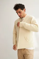 Campera tejida color marrón claro con cierre delantero, cuello alto y bolsillos delanteros. Tejida en 100% lana fina sin teñir.