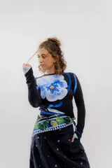 Pañuelo cuadrado de seda con estampado floral y geométrico en tonos azules, verdes y blancos sobre fondo negro.