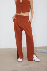 Pantalón de corte recto confeccionado en tela sastrera color ladrillo, con tajo lateral en la botamanga y bolsillos laterales.