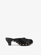 Zueco negro con capellada de pelo de becerro, base de madera con tachas doradas y tacón de cuero.