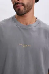 Remera oversize gris claro de manga corta, con estampa frontal pequeña y sutil con la inscripción Sailing Club.