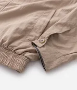Campera de sarga color beige con corte oversized, cuello de cuero sintético negro con textura trenzada, cierre frontal oculto y bolsillos laterales.