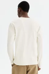 Remera de manga larga en tejido acanalado de algodón, color blanco, con cuello panadero redondo y tapeta corta con botones de ajuste. Corte slim fit que se ajusta a la silueta.