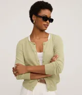 Cardigan de punto color verde claro, de manga larga y corte regular, con escote redondo y cierre frontal de botones.