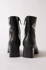 Bota de caña media con textura de reptil en color negro, punta cuadrada y taco bloque.