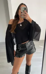 Capa o blusa de gasa negra, con mangas amplias y escote Bardot (hombros descubiertos).