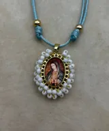 Collar ajustable con cordón azul y dije central ovalado con imagen religiosa, rodeado por una estructura de cuentas multicolores.