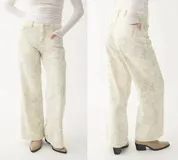 Pantalón de jean tiro medio, color crema o blanco roto, con estampado sutil en tono grisáceo. Corte recto o ligeramente acampanado.