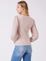 Buzo de tejido lurex marca Nanette, con cuello redondo y mangas largas con diseño plisado. Presenta puños ajustados con aplique de botones decorativos.