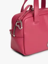 Cartera tipo bowling de Tommy Jeans, color fucsia, con doble asa superior y correa ajustable extraíble. Presenta logo metálico de la marca en la parte frontal.