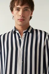 Camisa de mangas largas con estampado a rayas verticales en tonos verde oliva, blanco y azul. Corte regular y logo bordado en el pecho. Confeccionada en viscosa.