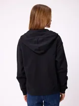 Canguro con cierre frontal de la marca Rusty, en color beige. Presenta capucha, bolsillos tipo canguro y logo bordado en el pecho.