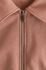 Buzo de algodón con interior cepillado, cuello camisero, medio cierre frontal y hombros caídos. Presenta puños y bajo acanalados.