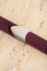 Cinto de cuero negro con textura de gamuza, presenta una hebilla metálica plateada de diseño clásico y puntera metálica a juego.