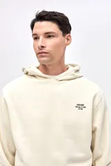 Buzo tipo canguro de felpa con friza, color beige, con capucha, bolsillos laterales y puños elásticos. Presenta arte de marca estampado en el pecho y en la espalda.