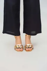 Sandalias bajas doradas con tiras anchas entrecruzadas en dorado y plateado, con pulsera al tobillo y taco cuadrado bajo.
