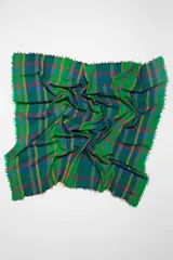 Chal cuadrado con diseño de cuadros en jacquard sobre fondo aguamarina y flecos en los bordes.