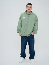 Campera rompevientos Umbro modelo Venti, de color negro con líneas blancas en las mangas y hombros, capucha con cordón de ajuste y cierre frontal completo. Cuenta con el logo de la marca bordado en el pecho.