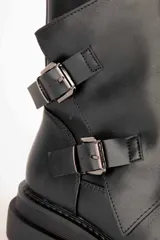 Bota de caña media color negro, de estilo biker, con suela chunky y dos tiras con hebillas metálicas en el lateral.