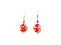 Pendientes colgantes Zévi dorados con estructura metálica en forma de hoja, decorados con una composición de cristales facetados en tonos rojos, fucsias y detalles grisáceos.