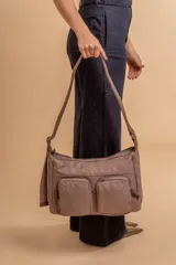 Bandolera de tafeta impermeable color beige, con dos bolsillos frontales con cierre y correa regulable. Diseño práctico y liviano ideal para uso diario.