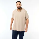 Remera polo de manga corta color beige, con cuello camisero sin botones y textura sutil de rayas verticales en relieve. Corte regular y diseño holgado.