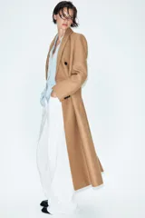 Abrigo largo negro ZARA Woman Collection de corte recto, confeccionado con hilatura de lana. Presenta cuello con solapa de muesca, cierre cruzado de doble botonadura frontal y bolsillos ribeteados en los laterales.