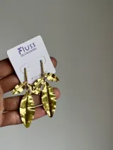 Aros colgantes dorados con forma de hojas texturizadas.