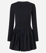 Vestido corto negro con parte superior ajustada de rib y falda globo de tricolina acanalada. Tiene cuello redondo y mangas largas.