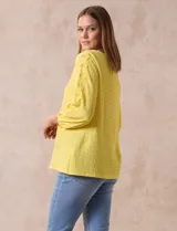 Blusa amarilla texturada con escote redondo y mangas 3/4 con puño elastizado. Aplique de broderie en escote y mangas. Marca Ruby Rd.