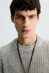 Camiseta de punto calado, color gris claro, de corte relajado (relaxed fit), con cuello redondo y mangas cortas.