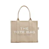 Bolso tote de gran tamaño Marc Jacobs, confeccionado en lona de algodón negra con el logo estampado en blanco en el frente. Cuenta con asas superiores reforzadas y una estructura amplia y resistente.