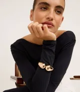 Pulsera dorada rígida con forma de gota doble.