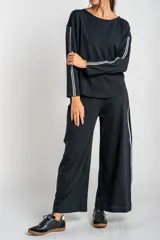 Pantalón negro de corte ancho con dos líneas blancas verticales en los laterales.