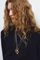 Pack de tres collares de estilo bohemio. Incluye un collar de cordón oscuro con nudos y dijes metálicos, un collar de eslabones metálicos con dijes variados y piedra de resina, y un collar doble de cadenas metálicas con dije de piedra engarzada en resina.