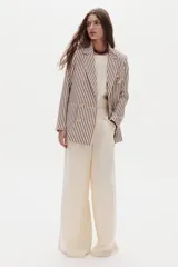 Blazer de lino color beige con diseño de rayas verticales bordó, de doble botonadura, solapas de muesca y bolsillos delanteros con solapa.