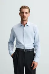 Camisa blanca de manga larga con cuello italiano y cierre frontal de botonadura. Corte regular fit.