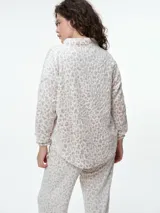 Buzo de dormir de tela fleece con estampado animal print en tonos grises y blancos. Presenta cuello alto con cierre de botones a presión y mangas largas.