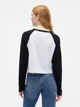 Remera de manga larga estilo raglán con cuerpo en color crema y mangas en color verde oscuro. Presenta un pequeño logo estampado en el pecho.