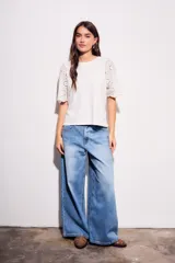 Remera de algodón peinado color negro, con mangas cortas de broderie con diseño calado y terminación festoneada. Presenta un corte oversize y cuello redondo.