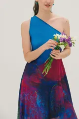 Vestido largo de fiesta con estampado abstracto en tonos azules, fucsia y violetas. Diseño de un solo hombro y falda con suave transparencia.