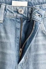 Jean de tiro alto con pierna amplia y corte holgado, confeccionado en denim rígido de tono azul claro con efecto desgastado. Presenta diseño clásico de cinco bolsillos, cierre frontal con botón y costuras reforzadas.