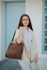 Cartera tipo bolso de hombro confeccionada en cuero marrón con textura acanalada horizontal. Presenta una estructura rectangular, correa de hombro ajustable y cierre superior.