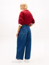 Jean de corte globo y talle alto, confeccionado en tejido denim rígido de color azul. Presenta diseño de cinco bolsillos, cierre de cremallera con botón y efecto desteñido en muslos y cadera.