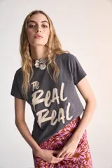 Remera gris de algodón con cuello redondo, manga corta y estampa frontal con la frase "The Real Real" en color beige.